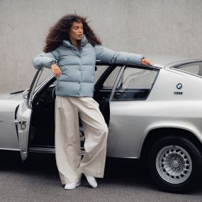 Nő BMW dzsekiben, autót támasztja